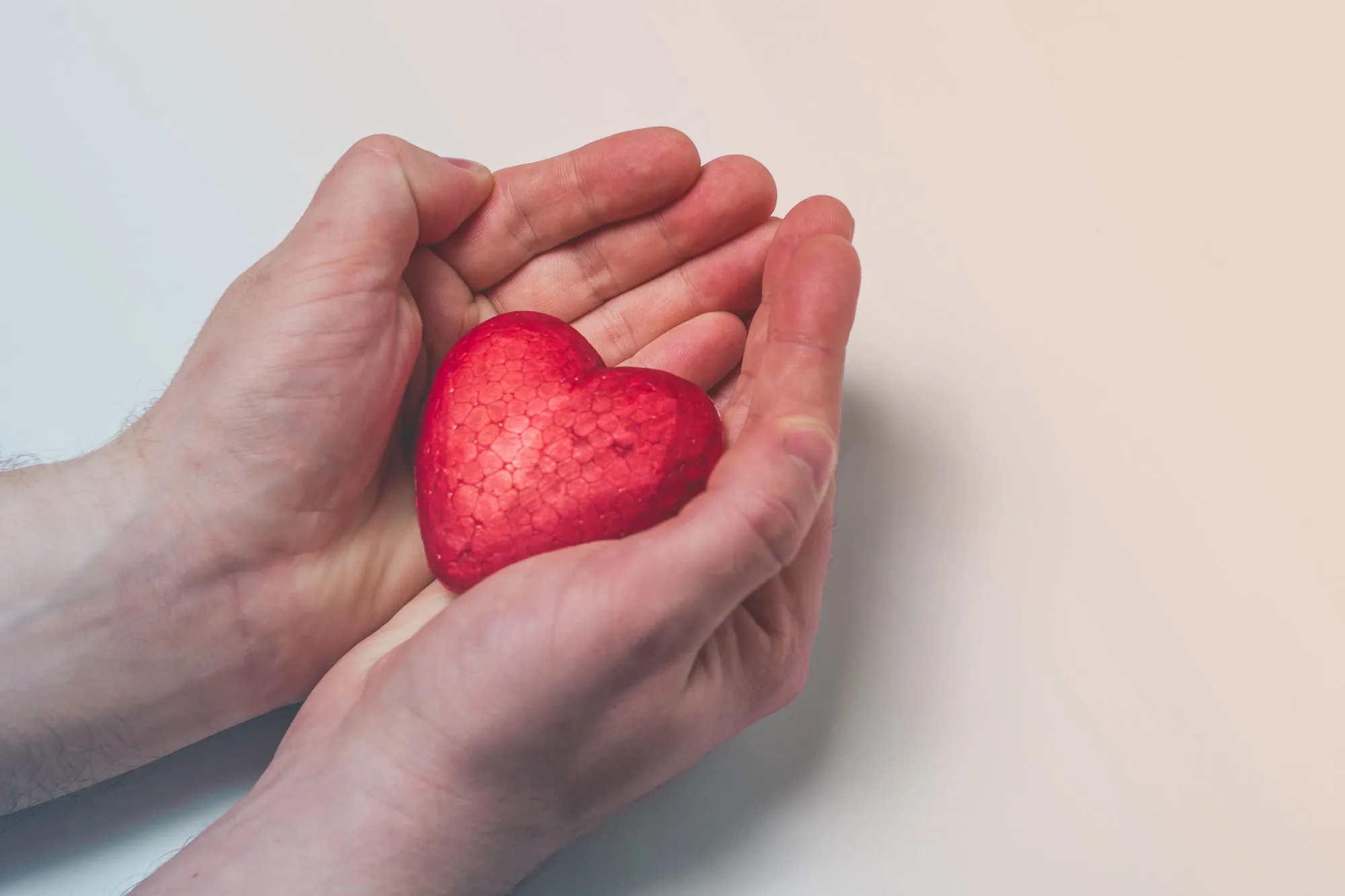 In den Händen einer Person liegt ein rotes Herz