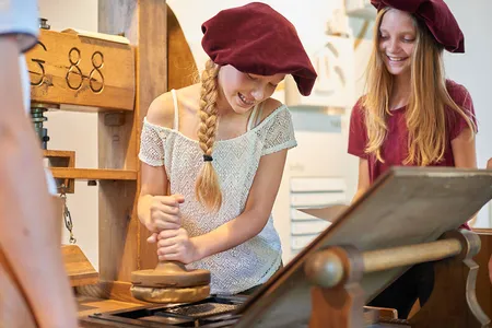 Jugendliche stehen an einer Druckerpresse