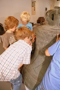 Kinder untersuchen eine große Glocke im Westfälischen Glockenmuseum in Gescher
