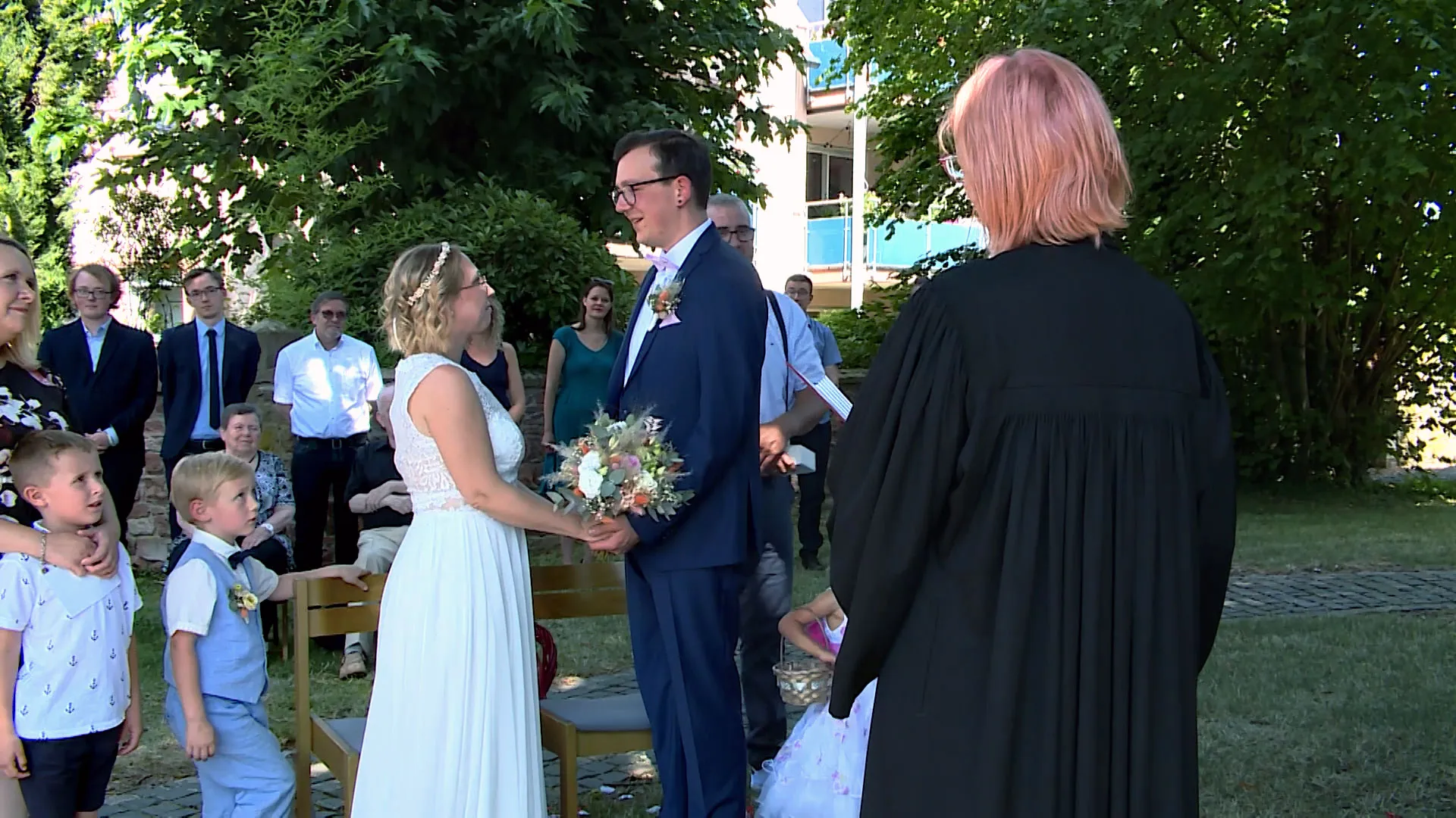 Brautpaar umrahmt von Pfarrerin und Familie