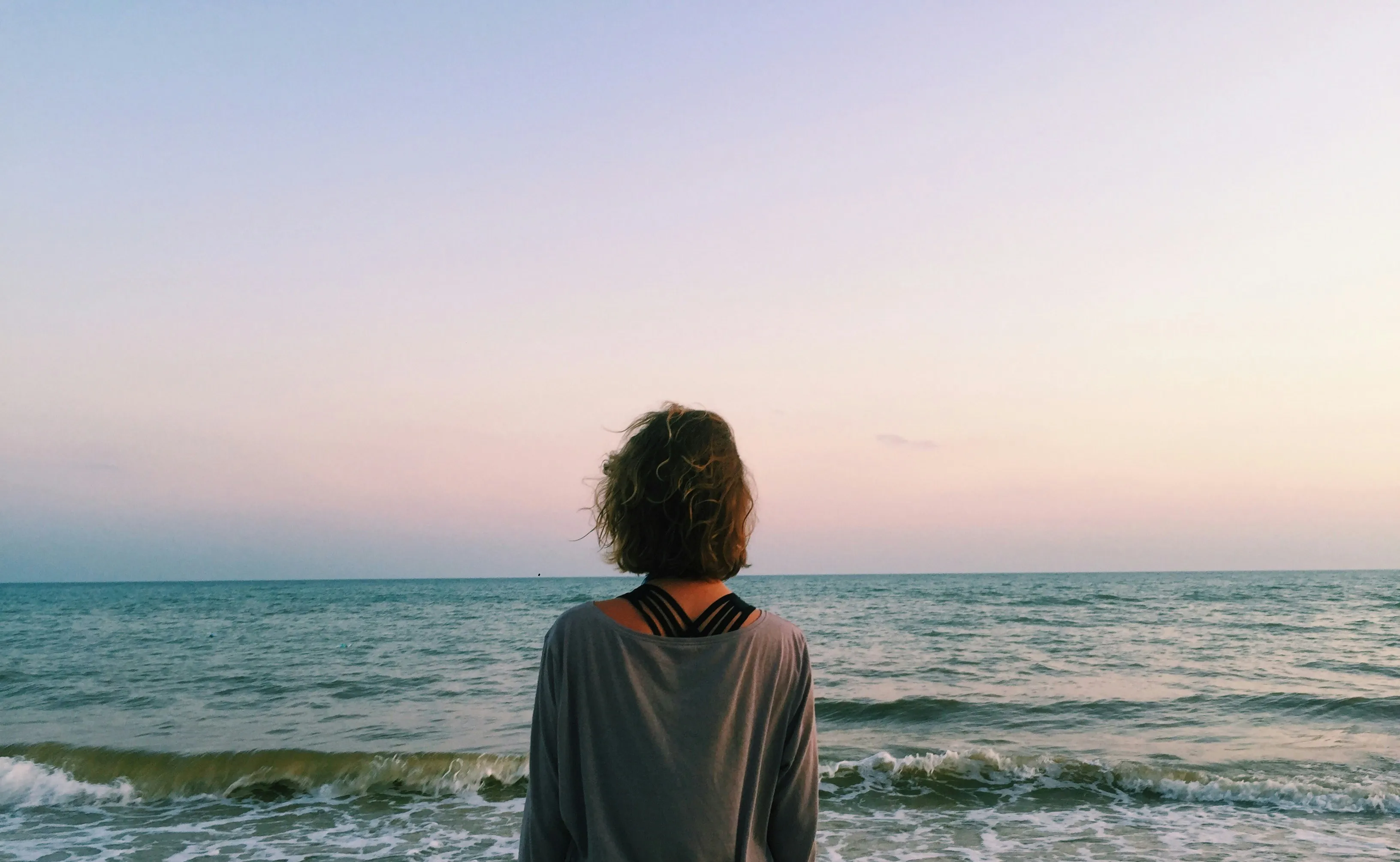 Frau, von hinten zu sehen, blickt auf Meer