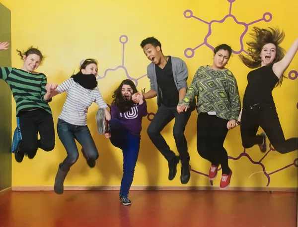 Sechs Jugendliche springen in die Höhe, halten sich an den Händen