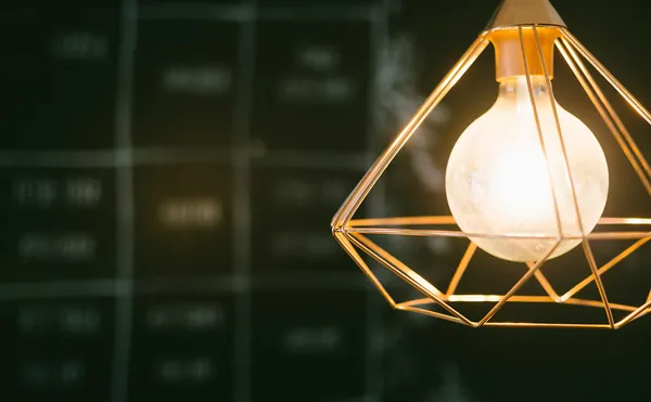 Glühbirne in einem Drahtgestell leuchtet in einen dunklen Raum