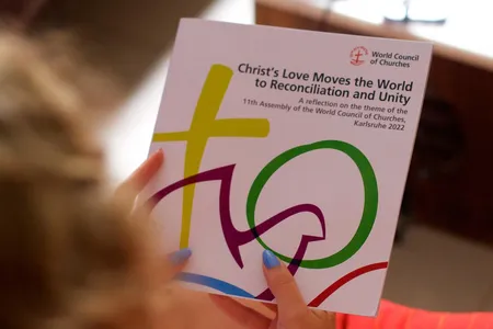 Eine Person hat eine Flyer zur Vollversammlung in der Hand