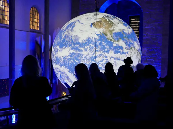 Menschen schauen von der Empore der Karlsruher Stadtkirche auf die große Weltkugel