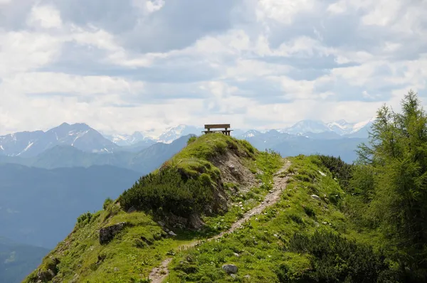 Bank an Wanderweg mit Blick auf die Berge