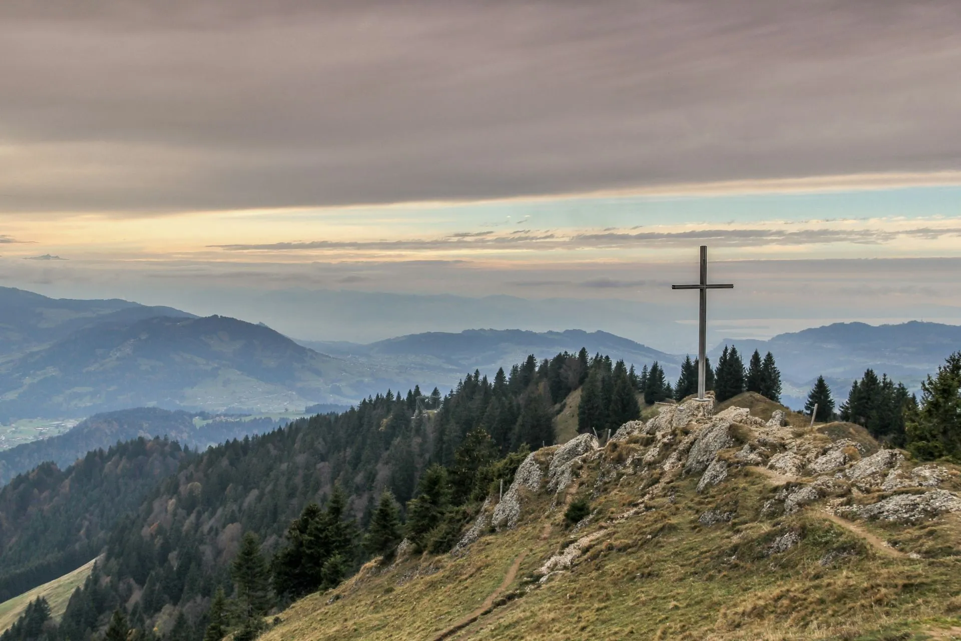 Blick von einer Anhöhe über Berge, mit großem Kreuz