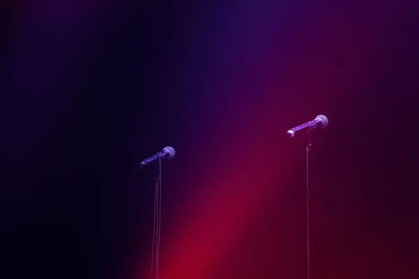 Zwei Mikrofone stehen nebeneinander auf einer Bühne