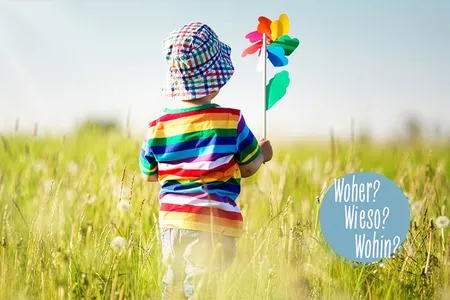 Kind mit Windrad in einer Wiese und Frage: Woher? Wieso? Wohin?