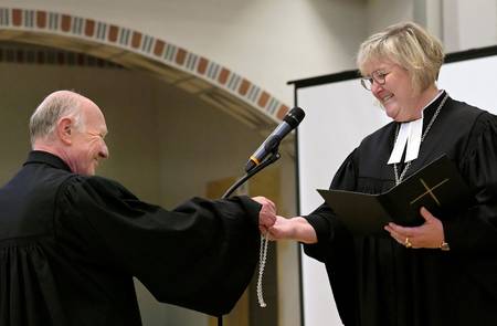 Urs Keller übergibt Landesbischöfin Springhart seine Kette mit Kreuz