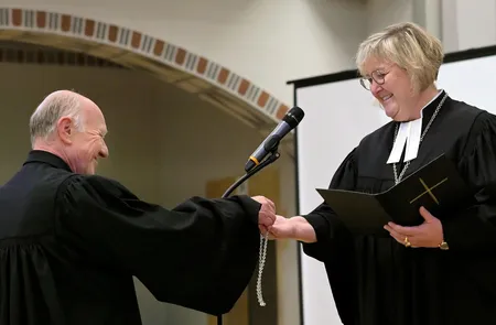 Urs Keller übergibt Landesbischöfin Springhart seine Kette mit Kreuz