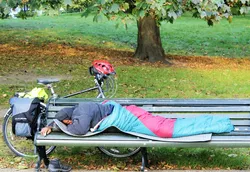 Mann im Schlafsack auf Parkbank