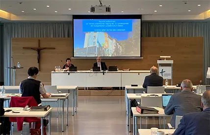 Präsidium der Landessynode vor großer Leinwand im Haus der Kirche