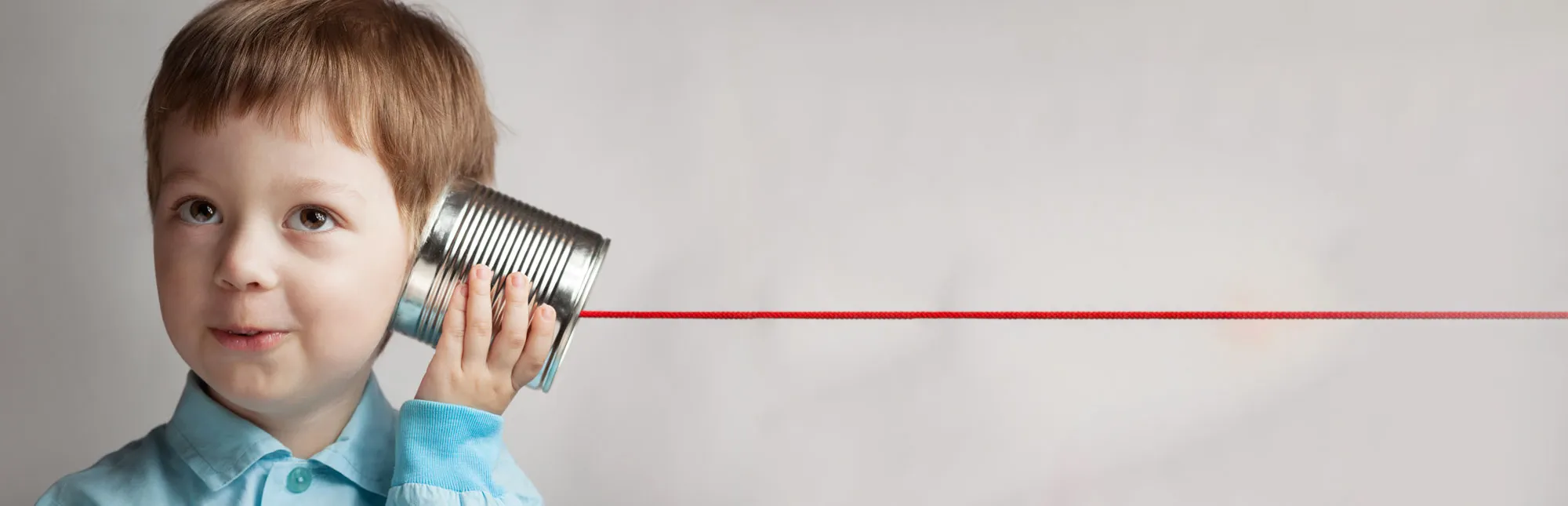 Kleiner Junge hält sich ein Schnurrtelefon ans Ohr und freut sich