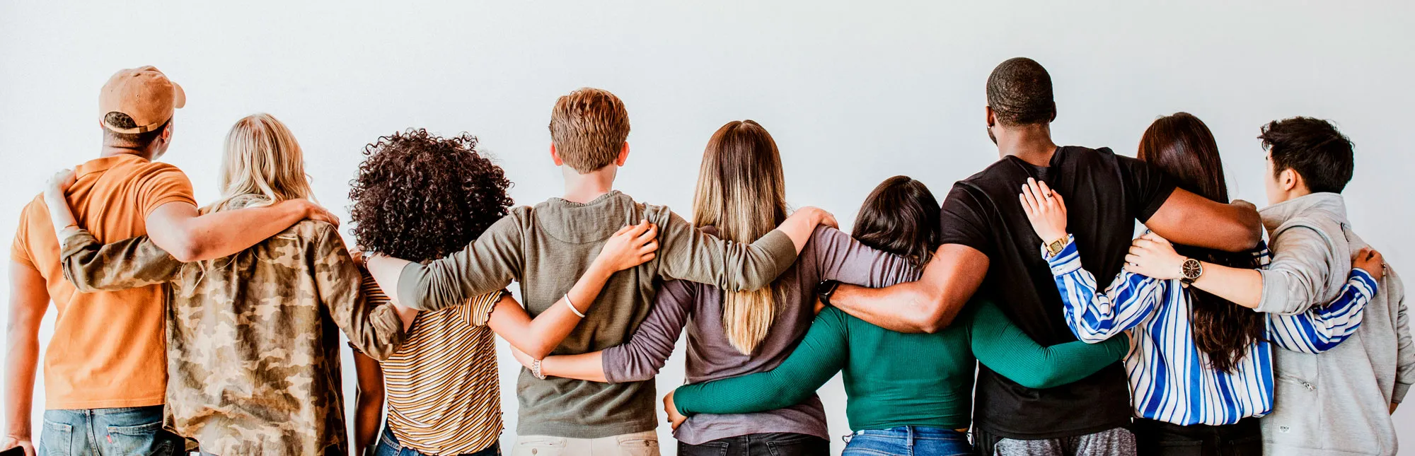 Blick von hinten auf eine Gruppe Menschen,  die sich die Hände auf die Schultern gelegt haben
