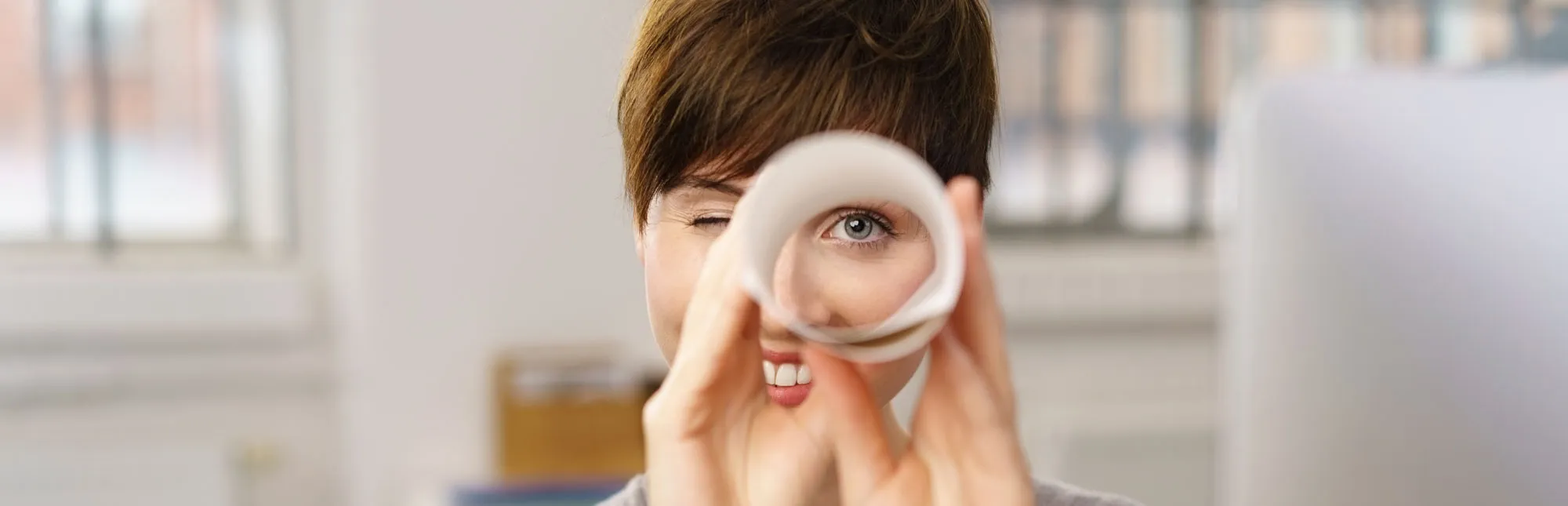 Frau schaut durch ein zusammengerolltes Papier