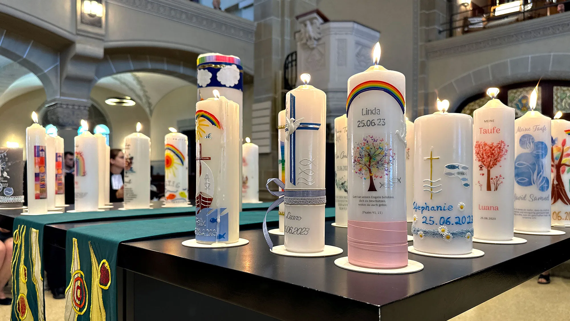Viele brennende Taufkerzen stehen auf einem Altar