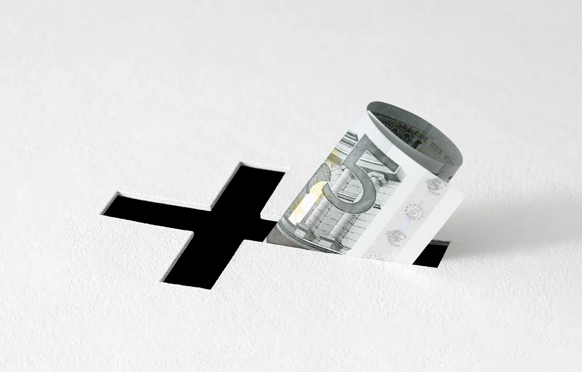 Ein Fünf-Euro-Schein steckt in einem Schlitz