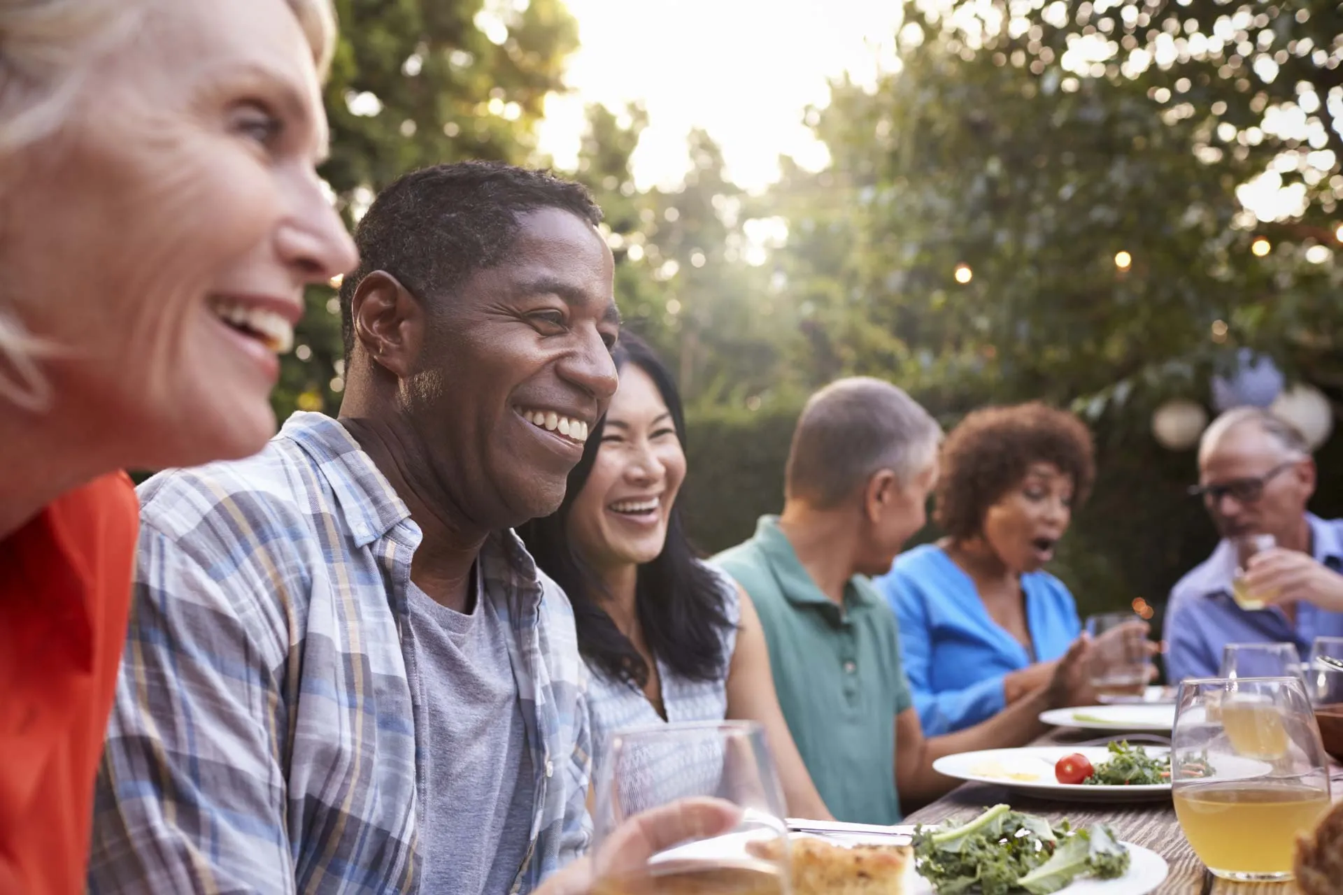 Lachende Personen verschiedener Nationalitäten sitzen an einem Tisch