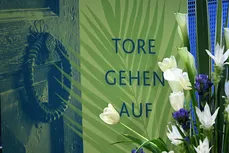 Schriftzug Tore gehen auf auf offenem Tor mit Blumenranke