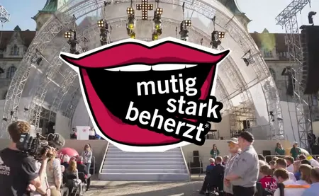 Quelle: Kirchentag.de Bühne in Hannover mit dem Logo mutig stark beherzt, ein gif lachender Mund aus dem die Worte kommen