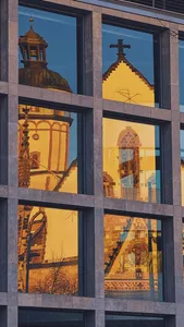 Die Leipziger Thomaskirche spiegelt sich in der Glasfassade eines modernen Gebäudes