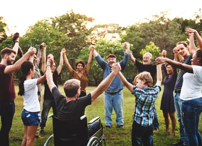 Quelle: adobestock Unterschiedliche Menschen halten sich in einem Park an den Händeninklusive Menschengruppe