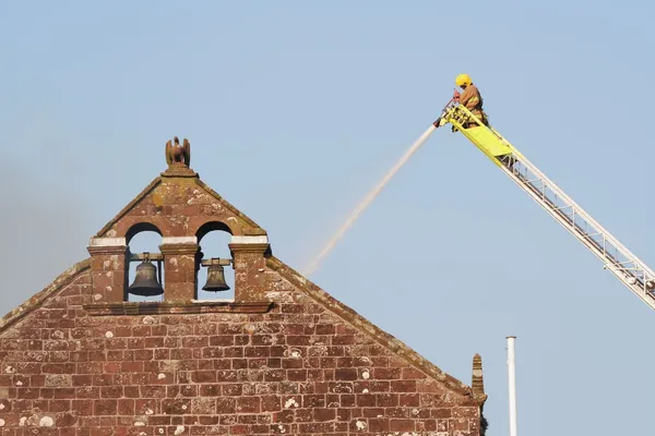 Quelle: AdobeStock Kirchengiebel mit Feuerwehrmann auf Drehleiter