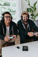 zwei junge Männer sitzen zusammen auf der Couch und spielen mit Controllern ein Videospiel. Sie haben Spaß.