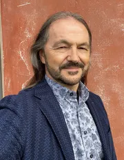 Portrait von Akademieleiter Dr. Gernot Meier im Anzug vor einer roten Wand