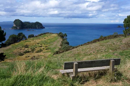 Alte Holzbank mit Blick für den Felsrand aufs weite Meer