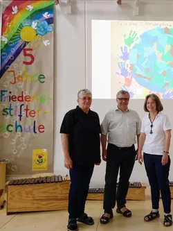 Die beiden Schulleiterinnen mit Stfan Maaß vor dem Trgernbogernplakt 5 Jahre Friedensstifterschule