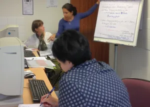 Drei Mitarbeiter Innen in einer Besprechung