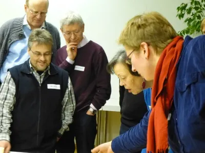 fünf Personen schauen interessiert auf einen Gegenstand