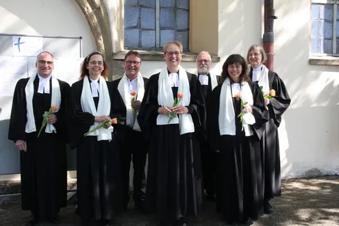 Pfarrinnen und Pfarrer des Gemeindeverbands tragen weiße Schals und eine Rose