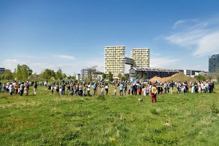 Eine große Gruppe von Menschen feiert auf einer weiten, grünen Wiese