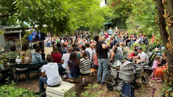 Eine Masse an Menschen sitzen im Garten