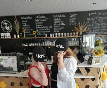 Zwei Frauen stehen vor einer Kaffeetheke mit einer Kappe, die licht. sagt