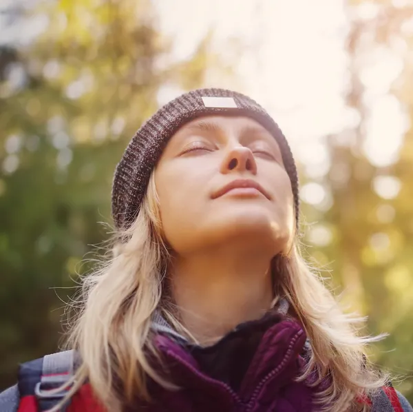 Portrait einer blonden Frau, sie hat ihre Augen geschlossen, der Kopf nach oben geneigt und atmet tief ein