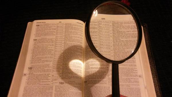 Bibel mit Lupe und Herz im Brennglas