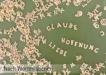 Buchstabensalat auf grünlichem Hintergrund. Auf einer etwas  freienFäche sindaus den Buchstaben die Worte "Glaube Hoffnung und Liebe gelegt. Unten stehen die Worte: "Nach Worten suchen"