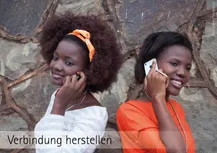Zwei dunkelhätige junge Frauen stehen vor einer Steinwand mit dem Rücken leicht schräg zueinander. Jede hat ein Telefon am Ohr. Darunter stehen die Worte: Verbindung herstellen