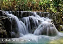 Im Hinergrund Bäume, vielleicht ein Wald. Im Vordegrund ein breiten Wasserfall bei dem das Wasser über unterschiedlich große Felsbrocken herunterstürzt. Danrunter die Worte "Gefühlen Raum geben"