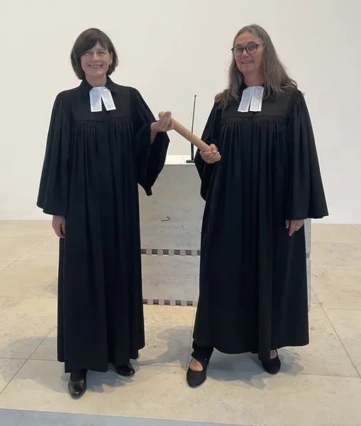 Pfrin Sabine Kast-Streib steht zusammen mit Pfrin. Judith Winkelmann vor dem Altar. Zwischen Ihnen der Stab den beide am jeweils anderen Ende festhalten.