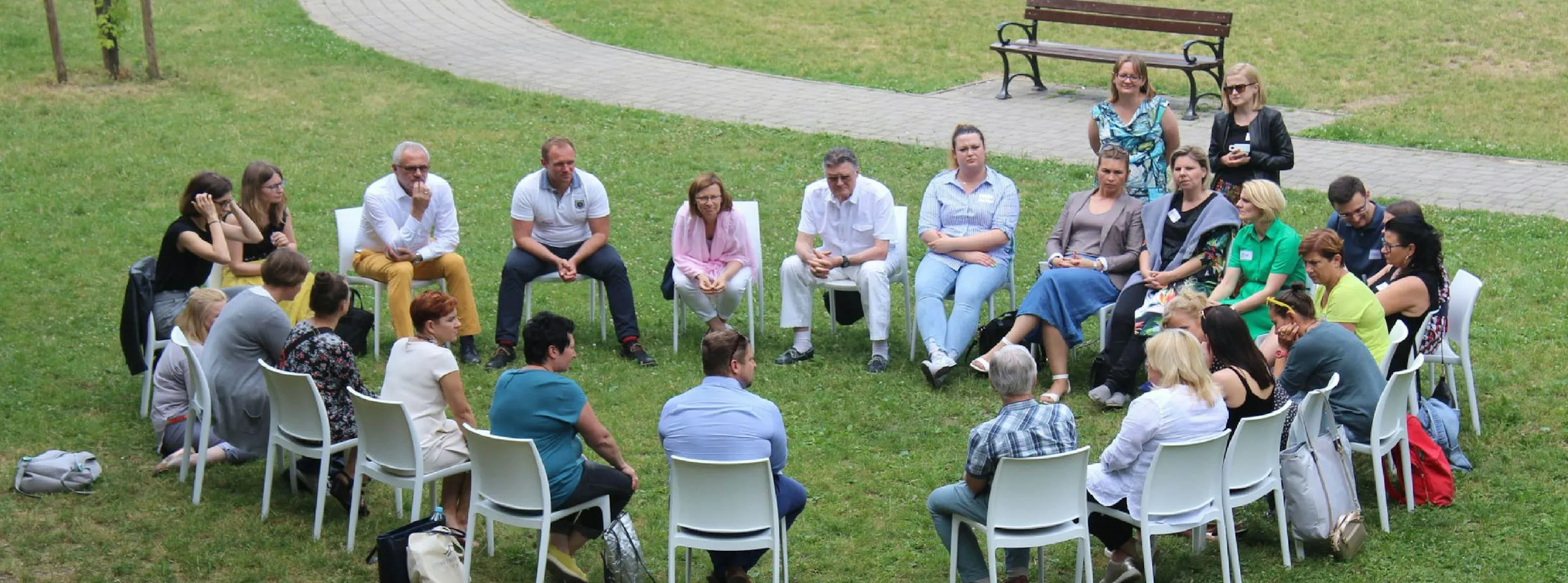 Gruppenbild Worksop aller Teilnehmenr sitzen in einem Stuhlkreis auf einer Wiese