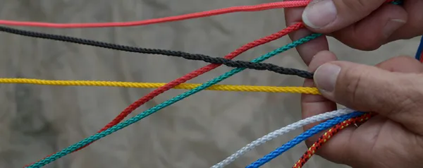 Hier sehen Sie bunte Fäden, die miteinander verwoben werden