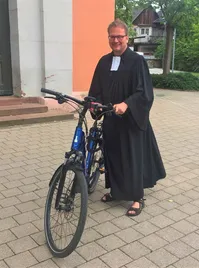 Quelle: bo.de Pfarrer in Talar auf einem Fahrrad