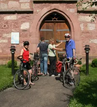 Quelle: Tourismusverband "Liebliches Taubertal" e.V. Gruppe von Radfahrern stehen vor einer Kirche