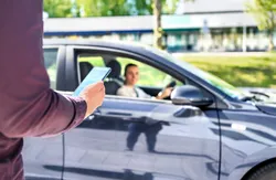 Quelle: © Tero Vesalainen- Adobe Stock Person läuft mit Smartphone auf stehendes Auto hinzu