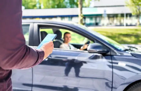 Quelle: © Tero Vesalainen- Adobe Stock Person läuft mit Smartphone auf stehendes Auto hinzu